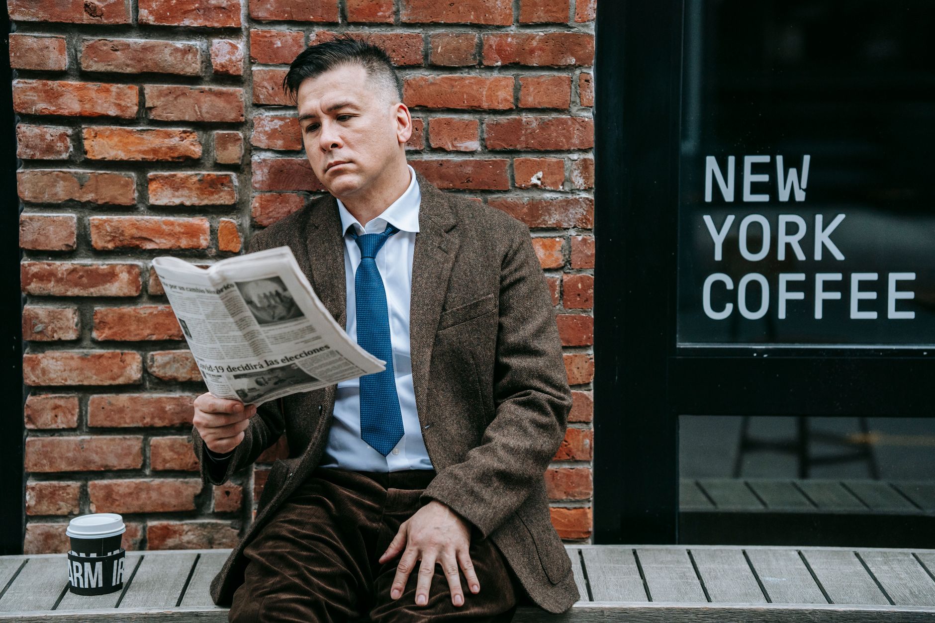 A professional man in formal wear reads a newspaper beside a coffee shop window. — So funktioniert die Registrierung bei High
